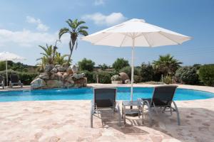 a pair of chairs and an umbrella next to a pool at Agroturismo Son Juaneda in Ciutadella