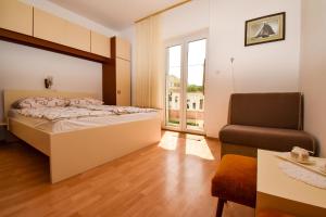 a bedroom with a bed and a chair and a window at Rooms Anđela in Rab