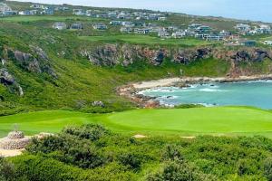 a golf course with a view of the ocean at Lodge 62 Unparalleled view. in Mossel Bay