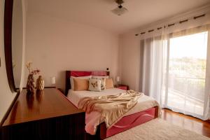 a bedroom with a bed and a desk and a window at Bairos House - Coastal Escape in Ribeira Brava