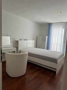 een witte slaapkamer met een bed, een bureau en een stoel bij Gemütliches Haus in Knonau in Knonau