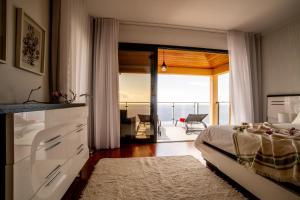 a bedroom with a bed and a view of the ocean at Bairos House - Coastal Escape in Ribeira Brava