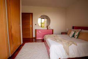 a bedroom with a large bed and a mirror at Bairos House - Coastal Escape in Ribeira Brava