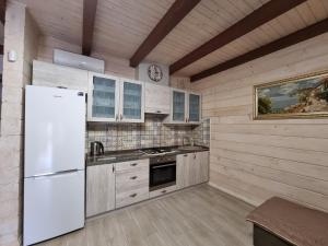 La cuisine est équipée d'un réfrigérateur blanc et d'un évier. dans l'établissement КОТТЕДЖ У МОРЯ, à Tchornomorsk