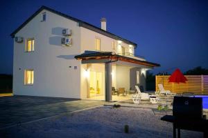 a large white house with a patio and umbrella at Villa Fiore in Žarović