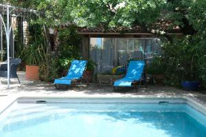 オペードにあるjolie location, maison avec piscine et joli jardin fleuri, à oppède dans le luberon en provence – 6 personnesの青い椅子とスイミングプール