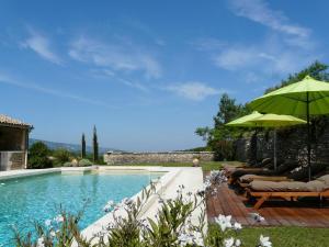 ラコステにある19th century Provencal Mas with pool in Provence in the Luberon, sleeps 6のプールサイドのパラソルとラウンジチェア付きのスイミングプールを利用できます。