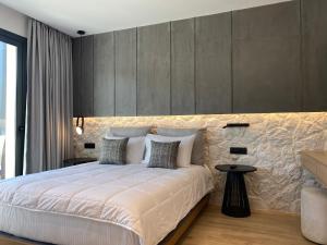ein Schlafzimmer mit einem großen weißen Bett und einer Wand in der Unterkunft Tramonto Maisonettes & Suites in Parga