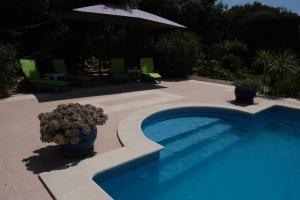 - une piscine avec un parasol et des chaises dans l'établissement pleasant villa located in aureille, close to the center by foot, in the alpilles park, sleeps 6., à Aureille