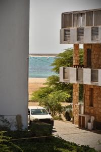 a building with a car parked on the beach at BoaOp Apartaments in Sal Rei