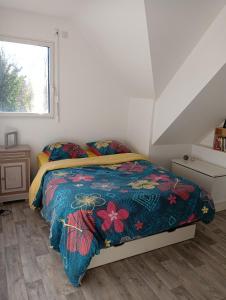 ein Schlafzimmer mit einem Bett mit einer bunten Bettdecke in der Unterkunft Maison au calme et proche de la mer in Arzal
