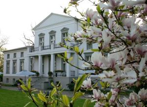 una casa blanca con una magnolia delante de ella en Dwór Podstolice - House of Rosenthal, en Podstolice