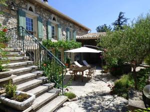 une maison en pierre avec des escaliers, une table et un parasol dans l'établissement Semi-detached provencal farm with swimming pool, à Orgon