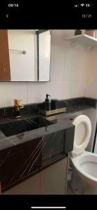 a bathroom with a toilet and a black counter top at Apartamento Cuiabá in Cuiabá