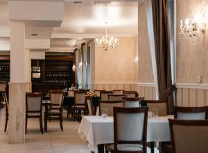 un restaurant avec des tables et des chaises blanches et un lustre dans l'établissement Hotel Pod Figurą, à Ogrodzieniec