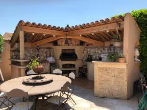 an outdoor kitchen with a table and a wooden pergola at pleasant home with private pool and pool house - close to aix en provence, accommodates 4 people. in Aix-en-Provence