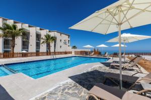 einen Pool mit Stühlen und Sonnenschirmen vor einem Hotel in der Unterkunft White Olive Elite Rethymno in Sfakaki