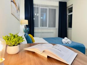 アルマトイにある417I3 Sky Blue Apartments Sholpan cityの寝室の木のテーブルの上の本