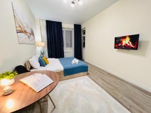 アルマトイにある417I3 Sky Blue Apartments Sholpan cityのベッドと机とテーブルのある寝室