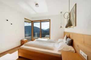 een slaapkamer met een groot bed en een groot raam bij Panoramasuite - Dahoam in Schenna
