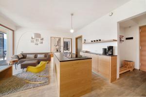 een keuken en een woonkamer met een bank en een gele stoel bij Panoramasuite - Dahoam in Schenna