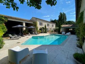 a swimming pool in front of a house at authentic provencal mas with pool, in the countryside of the village of sénas, close to the luberon and the alpilles, sleeps 8. in Sénas