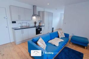 uma sala de estar com um sofá azul e uma cozinha em Charming 1 Bedroom Flat By J F SUITES Short Lets & Serviced Accommodation with WiFi em Kent