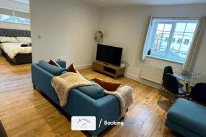 uma sala de estar com um sofá azul e uma televisão em Charming 1 Bedroom Flat By J F SUITES Short Lets & Serviced Accommodation with WiFi em Kent