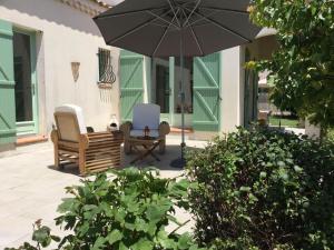 eine Terrasse mit 2 Stühlen und einem Sonnenschirm in der Unterkunft Jolie Maison de Vacances avec Piscine Privée, au cœur du village de Mouriès, dans le Parc Naturel Régional des Alpilles, 4 personnes LS1-298 PLANTARELLO in Mouriès