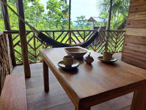 a wooden table with two cups and a hammock on a porch at Rainforest Hut in Archidona