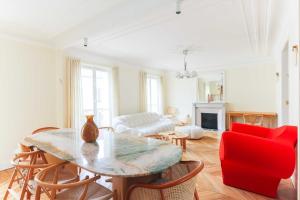 uma sala de estar com uma mesa e um sofá vermelho em Beautiful 95m2 flat in the heart of Neuilly Sur Seine em Neuilly-sur-Seine