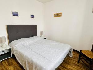 1 dormitorio con cama blanca y suelo de madera en Appartement Cambo-les-Bains, 2 pièces, 2 personnes - FR-1-495-112, en Cambo-les-Bains