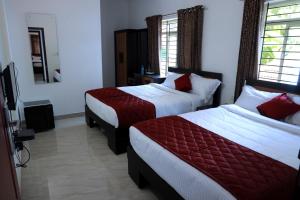 a hotel room with two beds and a mirror at NIDHI RESIDENCY in Guruvāyūr