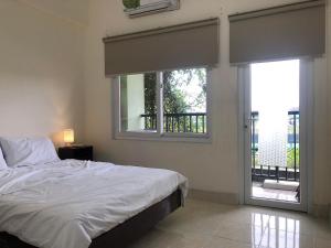 a bedroom with a bed and two windows at SARAH HOMESTAY in Thôn Lại Thê