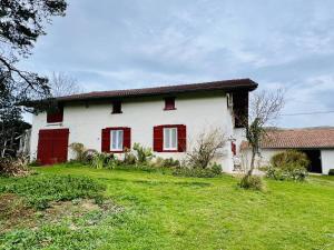 ein weißes Haus mit roten Fenstern und einem grünen Hof in der Unterkunft Maison Louhossoa, 4 pièces, 6 personnes - FR-1-495-134 in Louhossoa