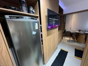 a kitchen with a refrigerator and a tv in a room at Ap Luxo Jardins Cd 707 in São Paulo