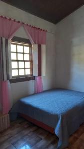 a bedroom with a blue bed and a window at Casa Nobre in Pirenópolis