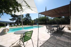 very beautiful villa with private pool in the luberon enjoying a magnificent view of the durance valley, located in puget – 10 people. في Puget: فناء مع طاولة وكراسي بجوار حمام سباحة