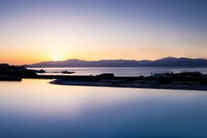 a swimming pool with the sunset in the background at Summer Senses Luxury Resort in Logaras