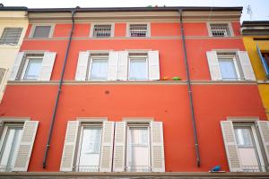 an orange building with white shuttered windows at Nido di Borgo35 in Parma