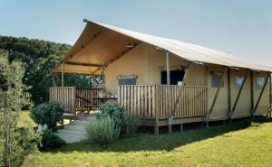 une tente jaune avec une table et une véranda dans l'établissement Easyatent Safari tent Bijela Uvala, à Poreč