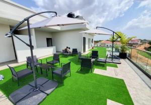 a patio with grass and chairs and an umbrella at The cozy standard studio in Madina
