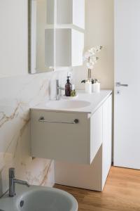 a white bathroom with a sink and a mirror at San Babila Design Apartment R&R in Milan