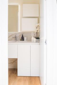 een witte badkamer met een wastafel en een spiegel bij San Babila Design Apartment R&R in Milaan
