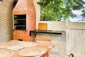 een patio met een bakstenen oven en een tafel en stoelen bij Casa do Píer in Governador Celso Ramos