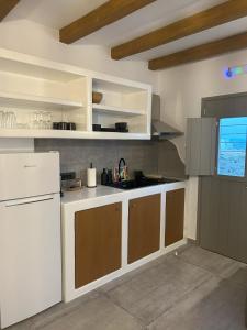 cocina con nevera blanca y armarios marrones en SOPHILIA SUITES, en Koufonisia