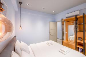 een slaapkamer met een wit bed en een spiegel bij Sleek Plaka Retreat - Heart of Athens in Athene