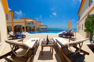 a patio with lounge chairs and a swimming pool at Belle View Hotel - Sea View & Sunset in Mánganos