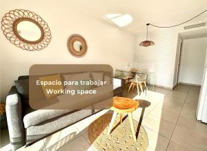 een woonkamer met een bank en een tafel bij Maracuyá con piscina, terraza, smart tv, cocina completa y WIFI in Corralejo
