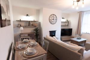 een woonkamer met een tafel, stoelen en een televisie bij Oak Cottage in Deepcar